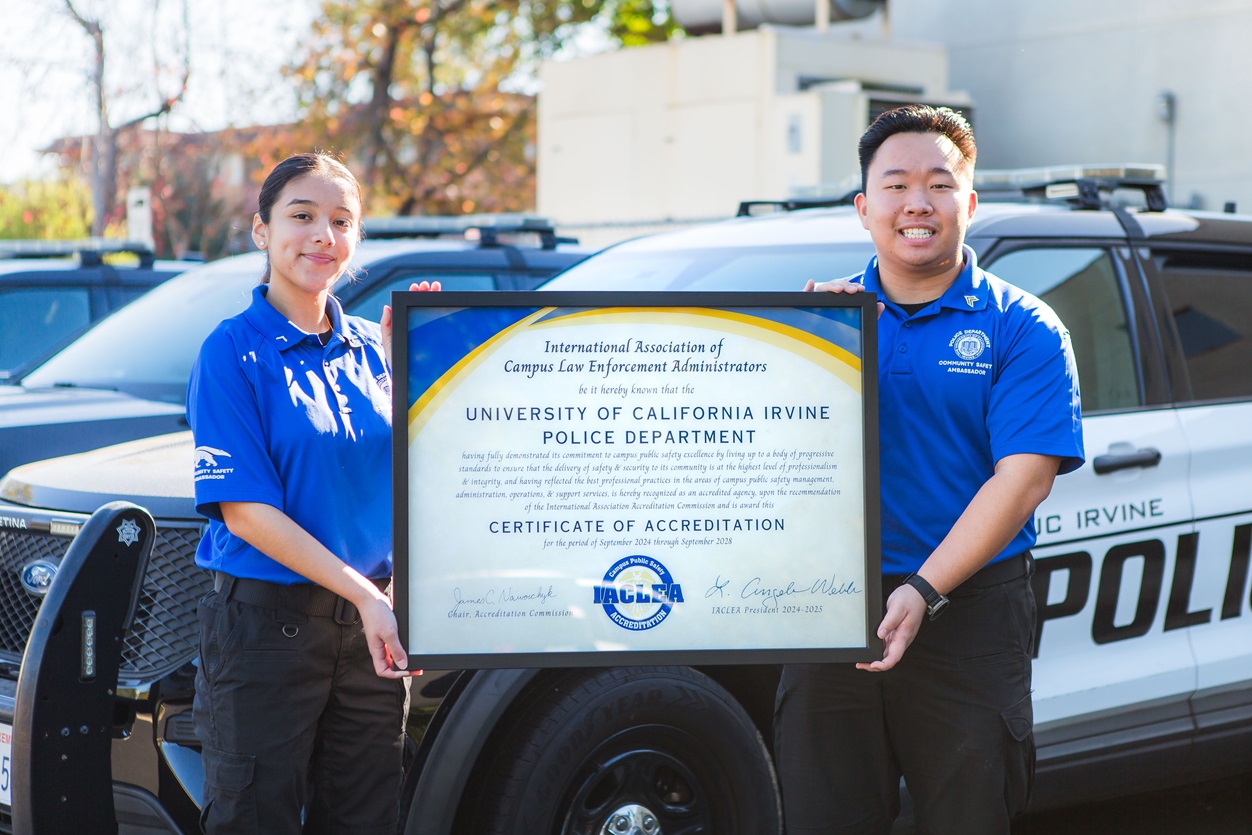 Two UCI Police student employees proudly hold up the IACLEA Accreditation Certificate